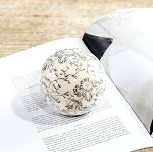 Decorative spherical object with floral patterns on an open book