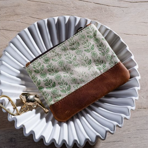 Fabric pouch with green leaf pattern on a decorative white plate