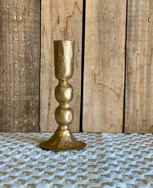 Gold candle holder on a textured surface with wooden background