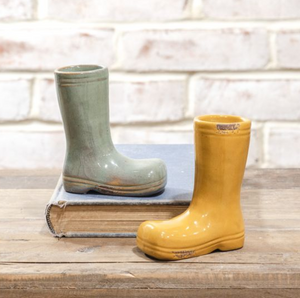 Green and yellow rain boots on a wooden surface with a white brick wall background