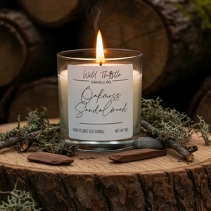 Candle with a label on a wooden surface with logs and natural elements in the background