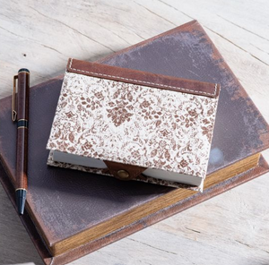 Floral-patterned journal on a textured surface with a pen