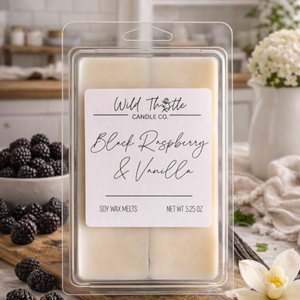 Package of soy wax melts labeled Black Raspberry and Vanilla with modern kitchen background and accents of black raspberries and white flowers.