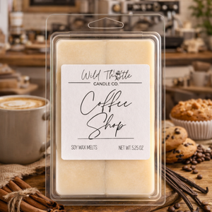 Packaged wax melts labeled 'Coffee Shop' by Wild Thistle Candle Co. on a wooden surface with coffee and pastries.