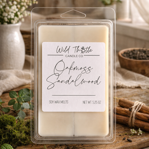 Pack of Wild Thistle Candle Co. Oakmoss Sandalwood soy wax melts on a wooden surface with decorative elements.